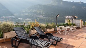 Una terraza con sillones de descanso negros y un cartel que indica un hotel.