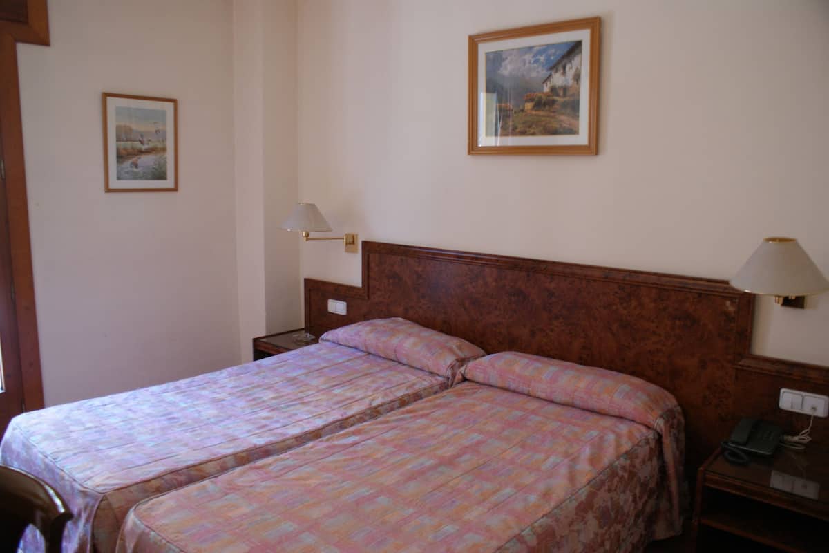 A double bed with a wooden headboard, a bedside table with a lamp, and a framed picture on the wall.