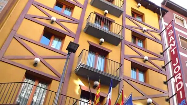 Un immeuble jaune doté de nombreux balcons et fenêtres, sur lequel on peut lire l’inscription « HÔTEL ».