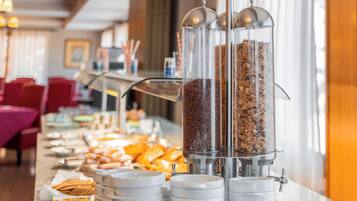 A buffet setup with coffee dispensers and a variety of pastries.