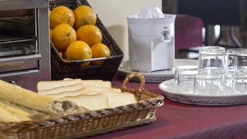 Een ontbijt met brood, sinaasappels, een sapcentrifuge en glazen op een tafel.