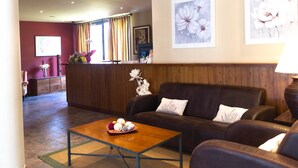 A lobby with a reception desk, a sofa set, a coffee table, and artwork on the walls. - Aparthotel La Vall Blanca (Vielha e Mijaran)