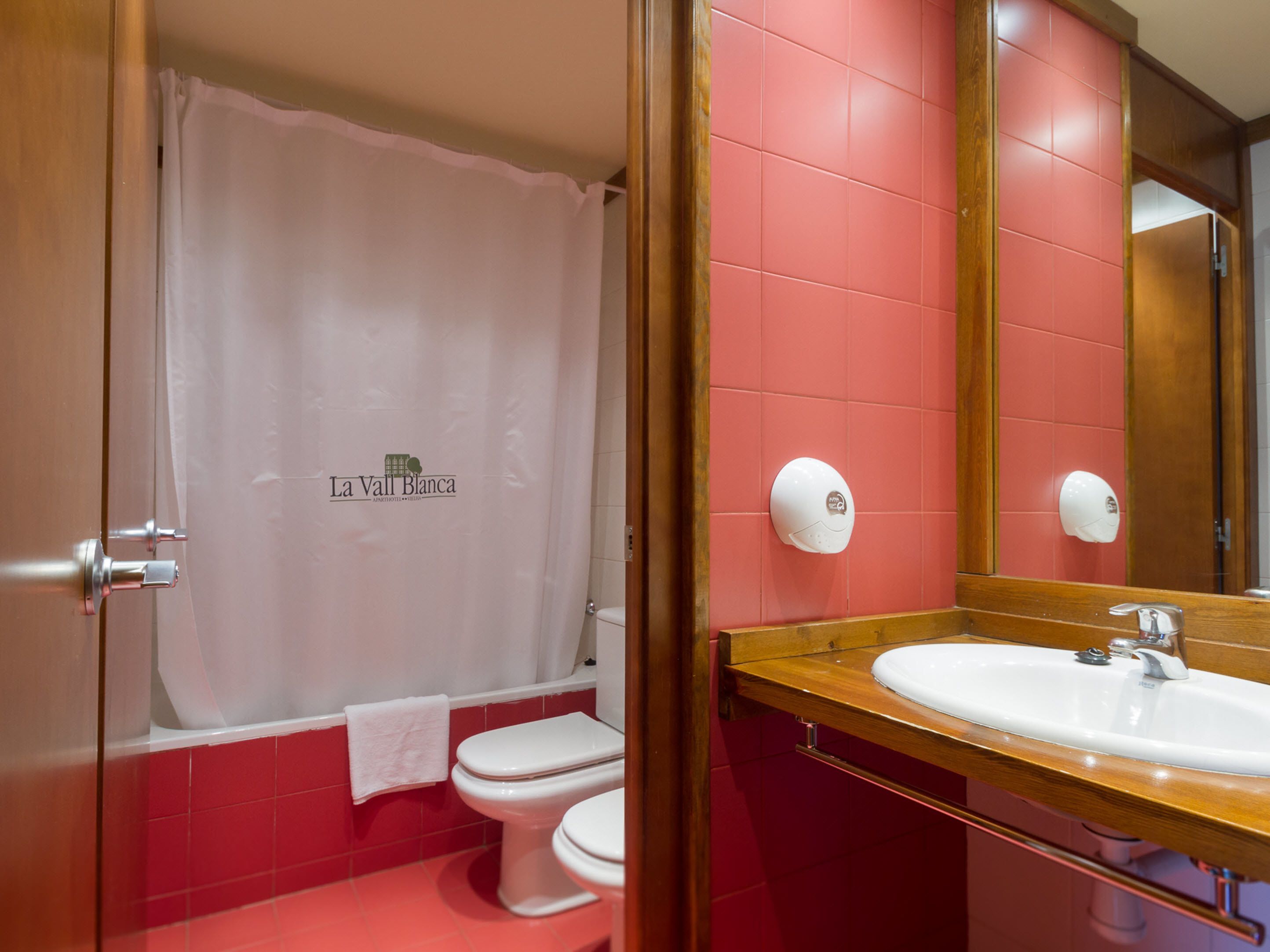 A bathroom with a white toilet, a shower curtain, and a sink with a mirror.