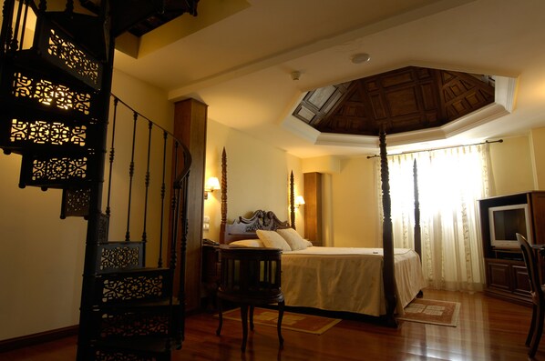 A bedroom with a four-poster bed, a television, and a staircase with intricate woodwork. - Hotel Domus Selecta Finca Eslava (Antequera)