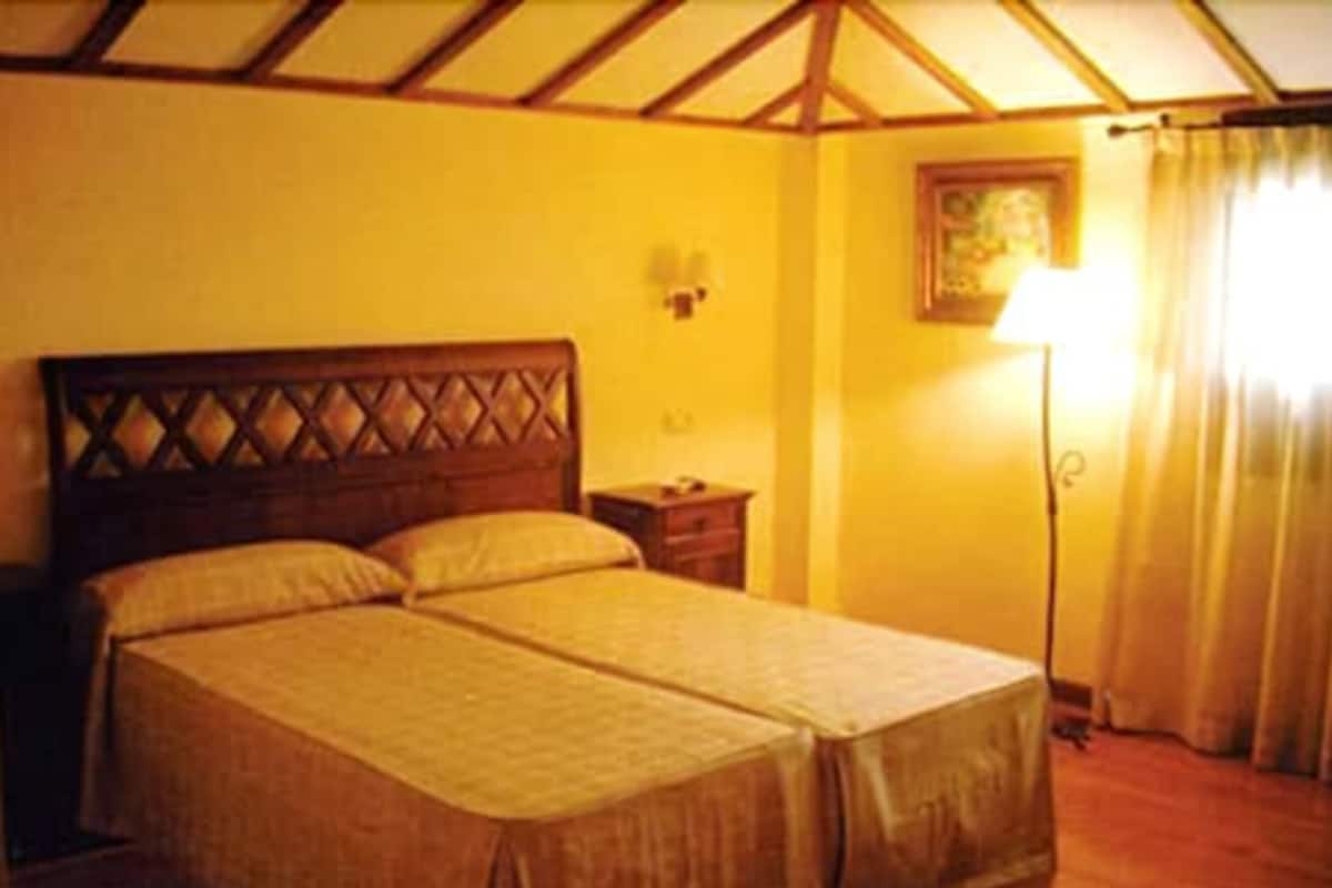 Ein Doppelbett mit Holzüberbau, ein Nachttisch und eine Lampe.