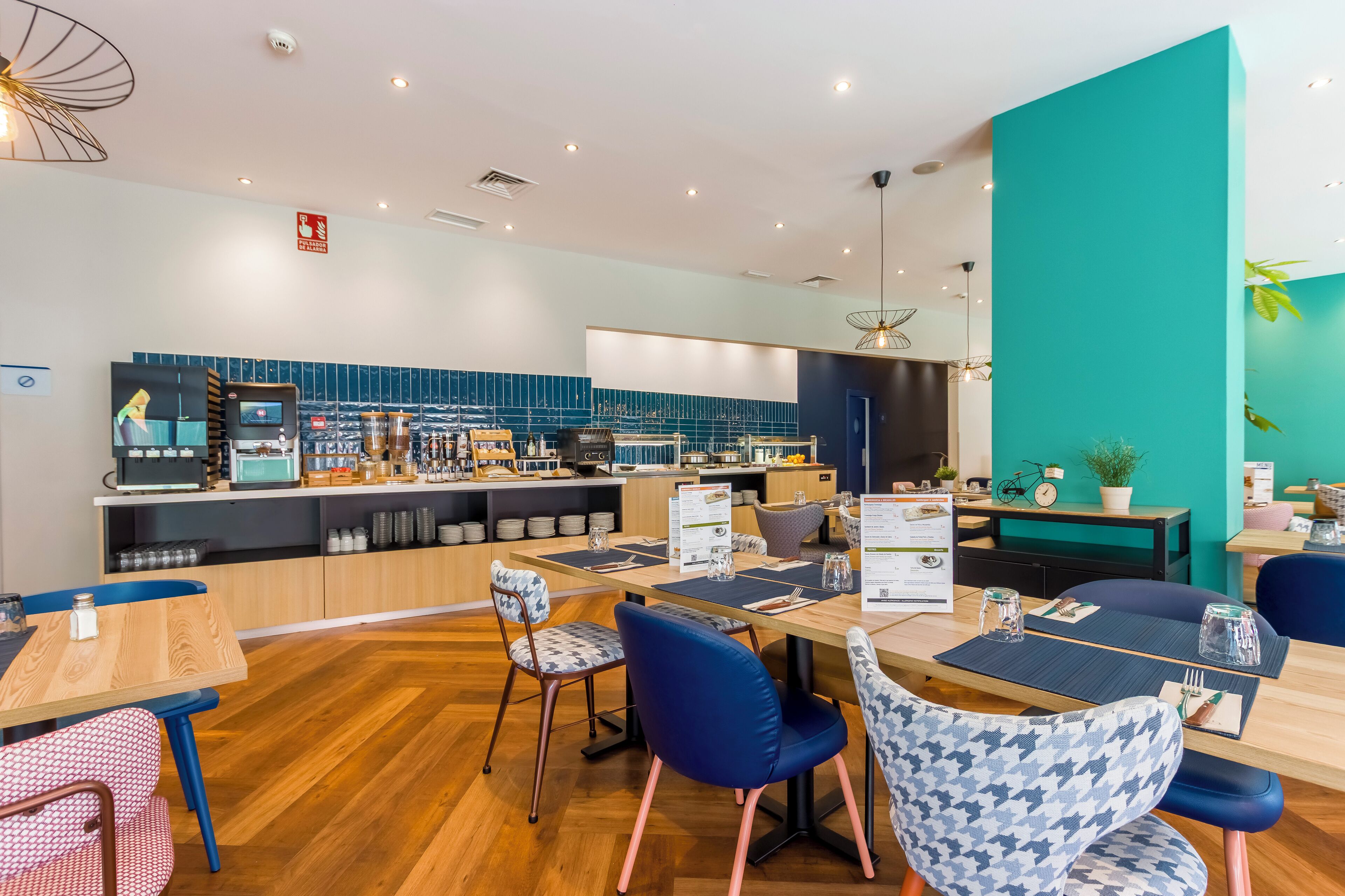 Un restaurante moderno con una pared de acento color turquesa, suelo de madera y sillas azules.