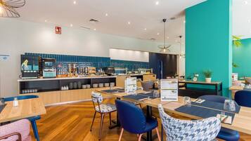 Un restaurante moderno con una pared de acento color turquesa, suelo de madera y sillas azules.