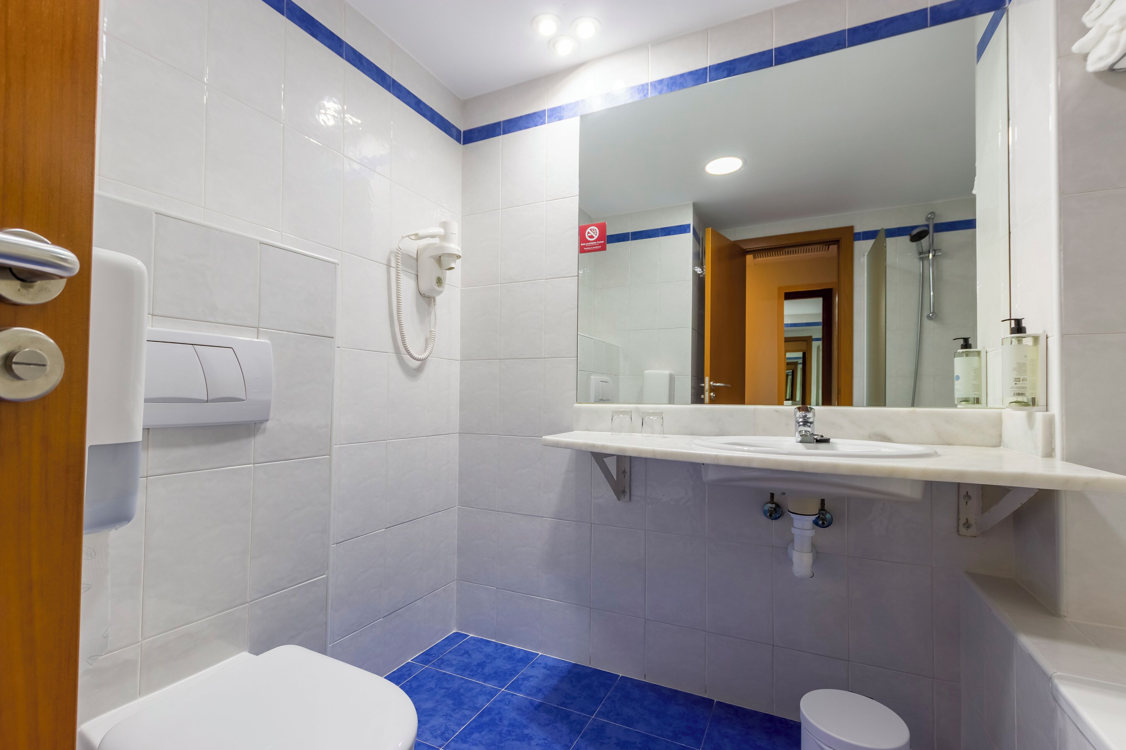 A bathroom with a white sink, mirror, and toilet.