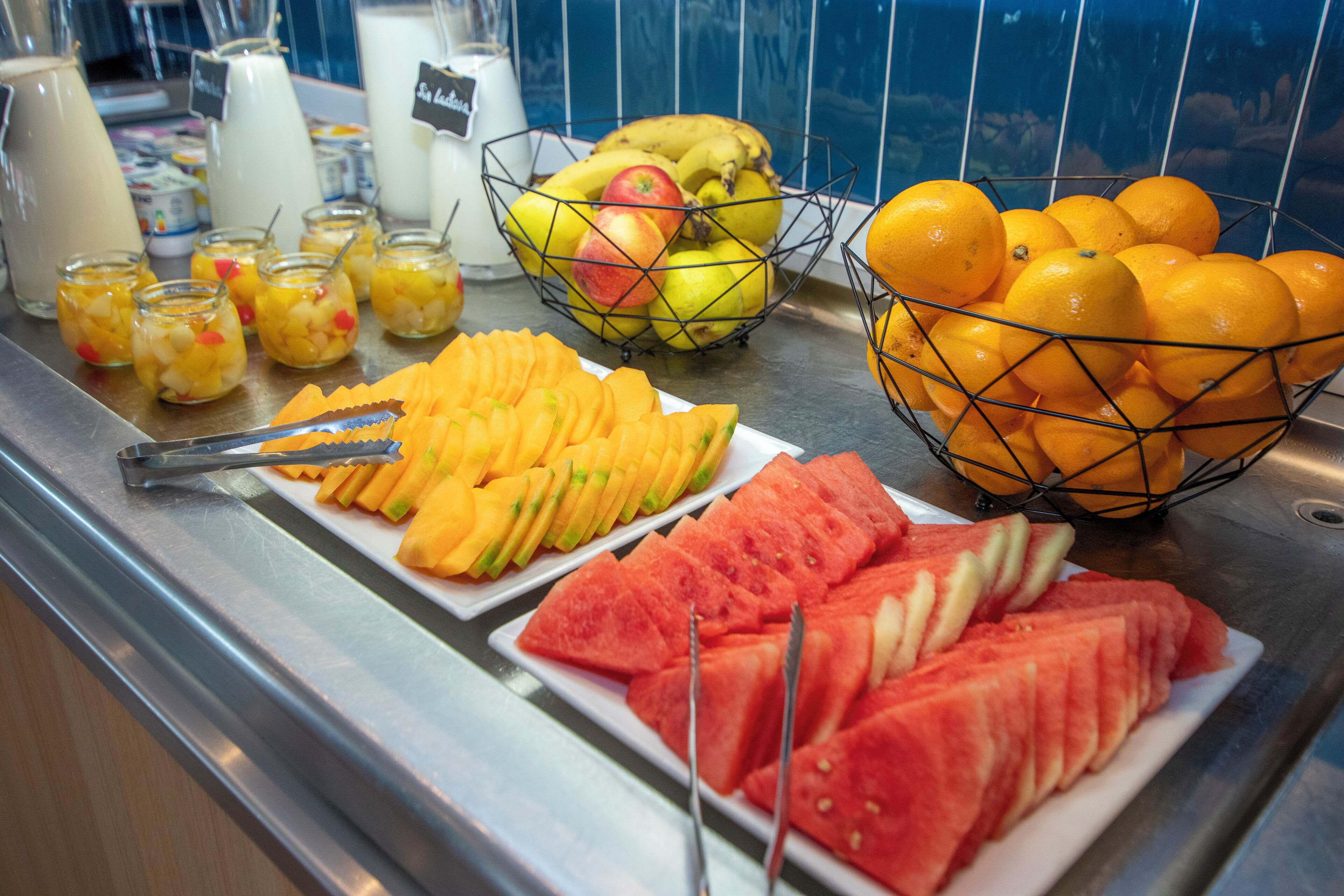Un bufé con diversas frutas y bebidas.