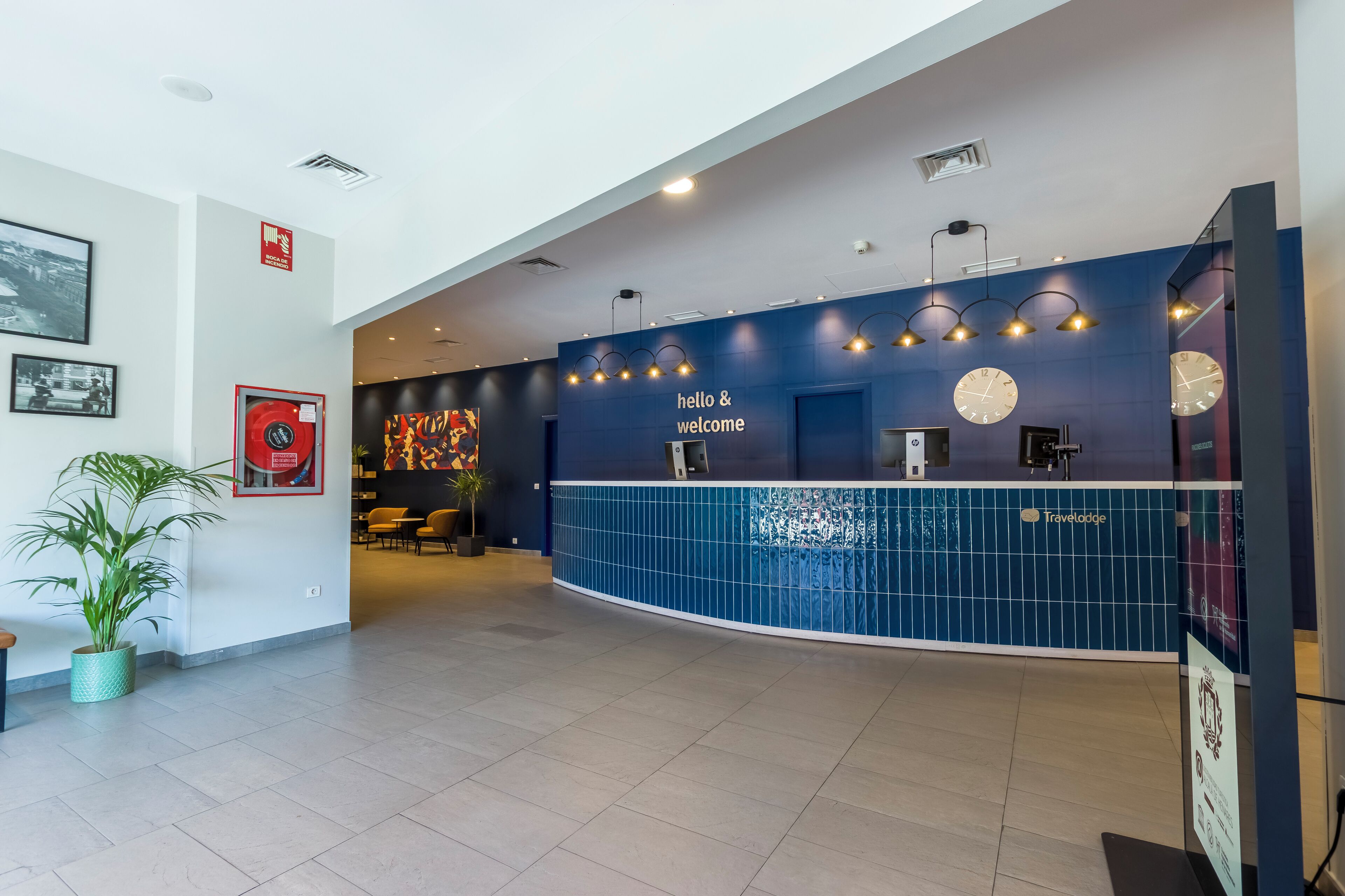 A reception area with a blue tiled wall, a clock, and a 'hello & welcome' sign.