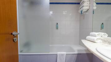 Een badkamer met een douchecabine van glas, een wit bad en een wastafel met spiegel.
