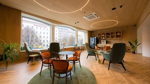 A modern interior with wooden floors, large windows, and a mix of seating arrangements including chairs and tables. - Hotel Beranek Prague (Prague)