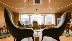 A modern interior with two green armchairs, a small round table, and large windows offering a city view. - Hotel Beranek Prague (Prague)