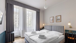 A hotel room with two beds, a round table, a chair, and a TV. - Hotel Beranek Prague (Prague)