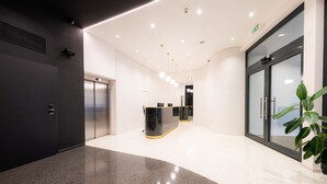 A modern reception area with a glass door, a reception desk, and an elevator. - Hotel Beranek Prague (Prague)