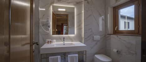A modern bathroom with a marble sink, a glass-enclosed shower, and a wooden door.