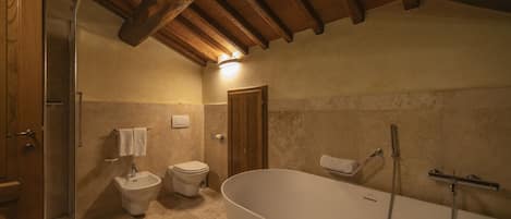 A bathroom with a freestanding bathtub, a bidet, and a toilet.