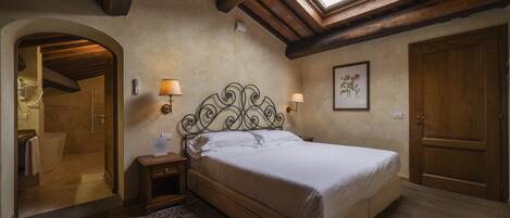 Une chambre à coucher avec un puits de lumière, un lit, une table de chevet, un miroir, une porte et une lampe fixée au mur.