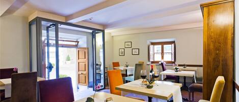 A dining area with tables and chairs, a wooden cabinet, and a view of the outside.