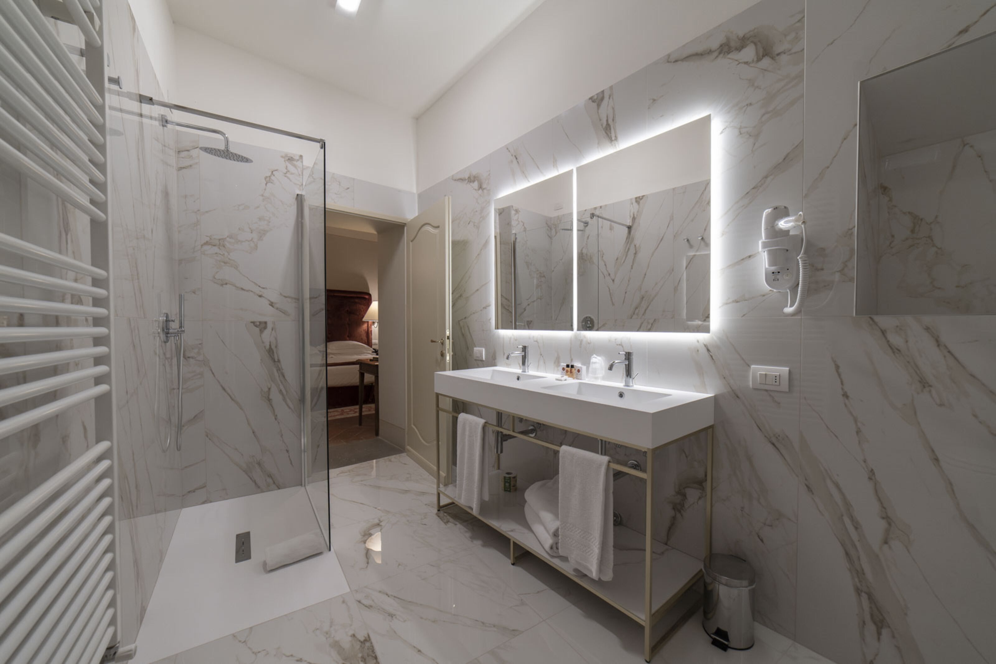 Une salle de bain moderne dotée d’une douche à parois de verre, d’un grand miroir et d  ’un meuble-lavabo à deux vasques.