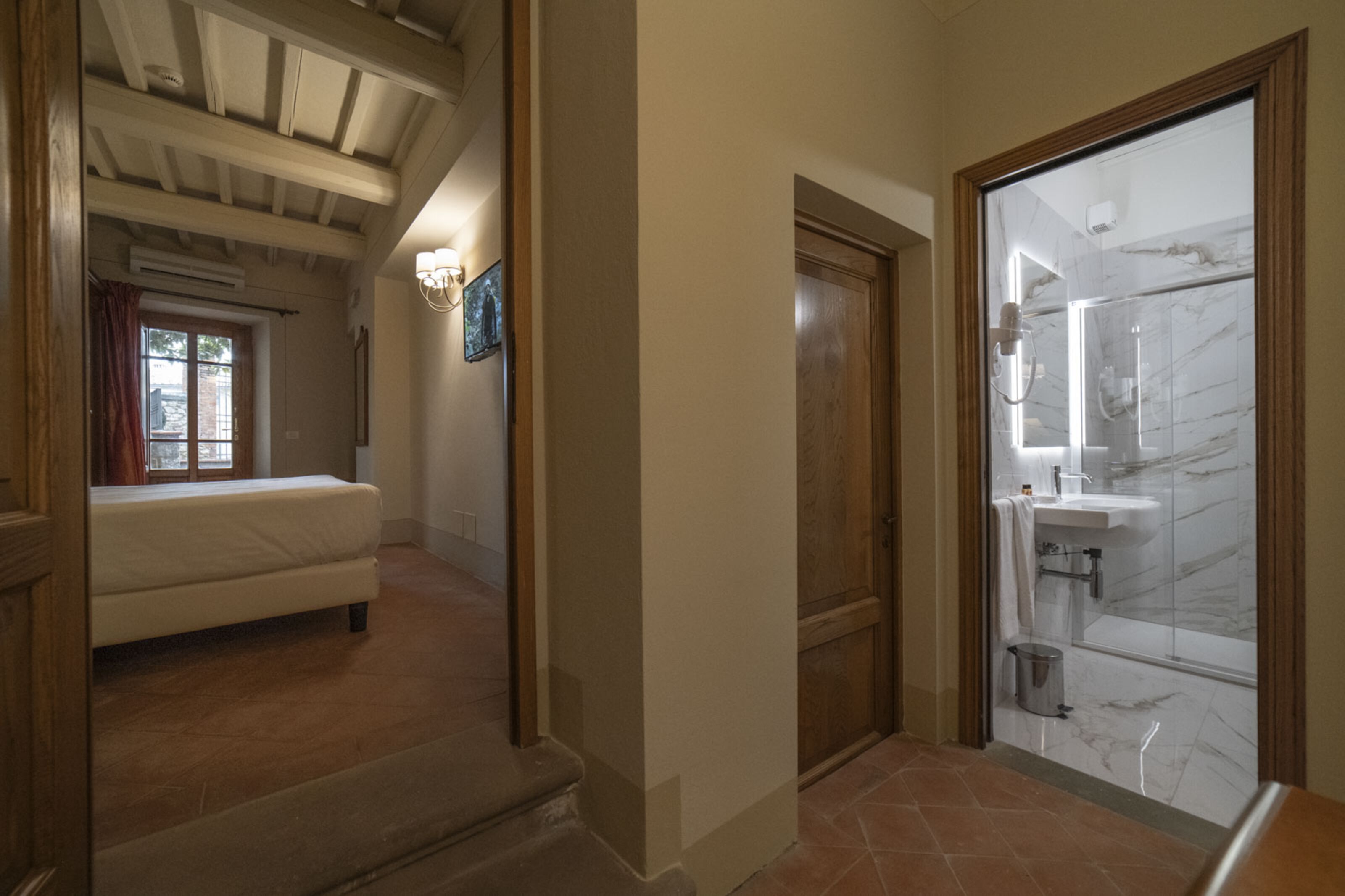 A hallway leading to a bathroom with a shower and a toilet.