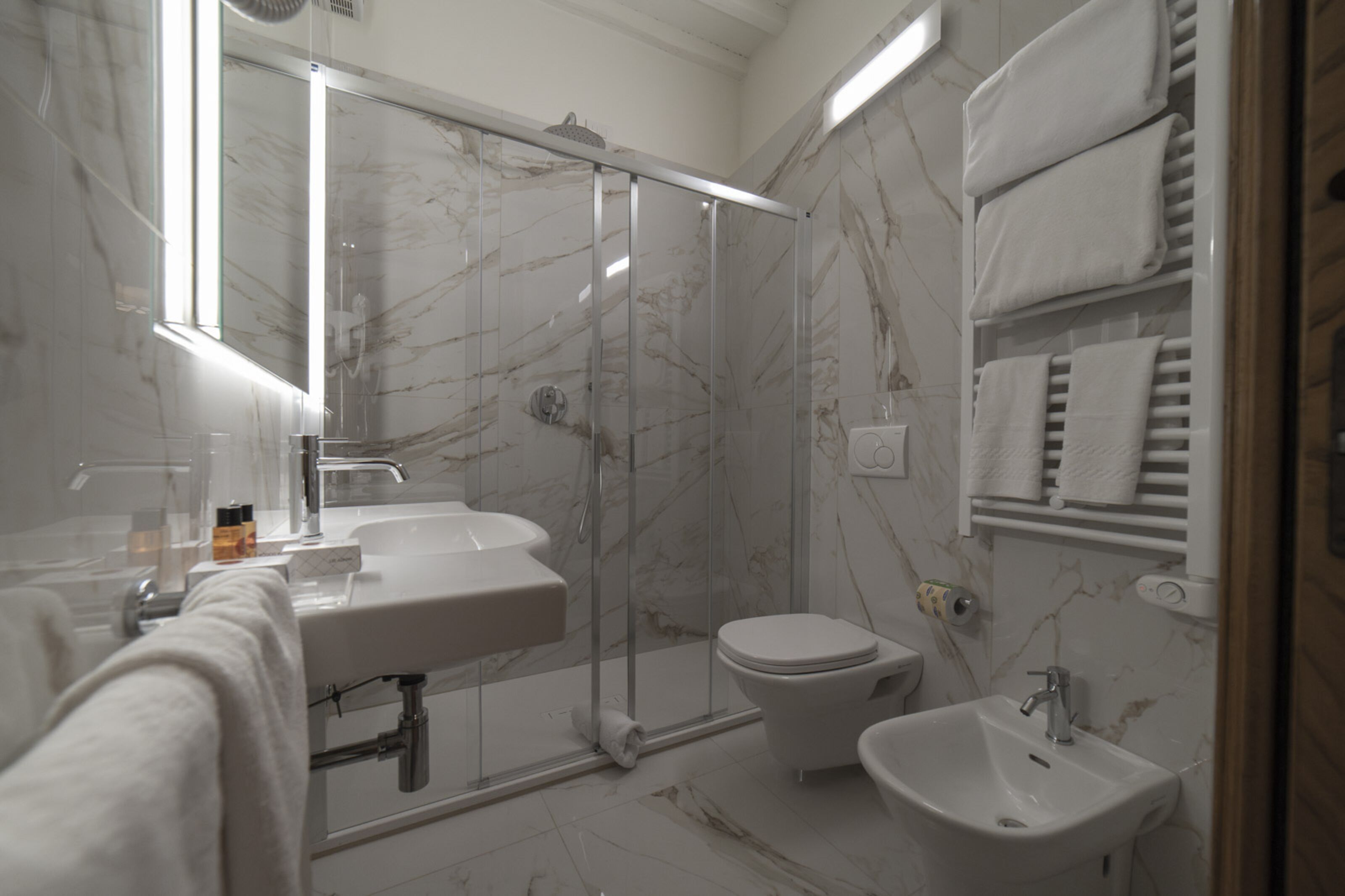 Ein modernes Badezimmer mit einer Duschkabine, einem Waschbecken, einer Toilette und einem Bidet.