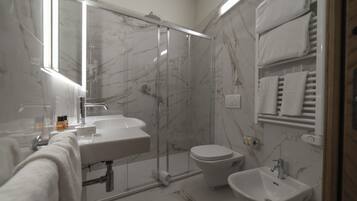 Ein modernes Badezimmer mit einer Duschkabine, einem Waschbecken, einer Toilette und einem Bidet.