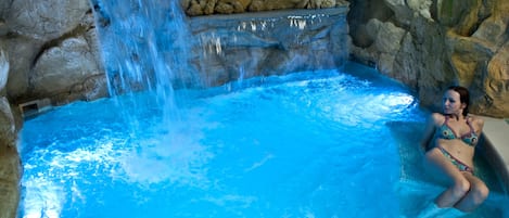 Una piscina cubierta, una piscina al aire libre, tumbonas