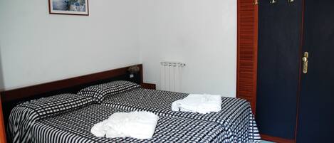 Ein Schlafzimmer mit Bett, Kleiderschrank und Heizkörper.