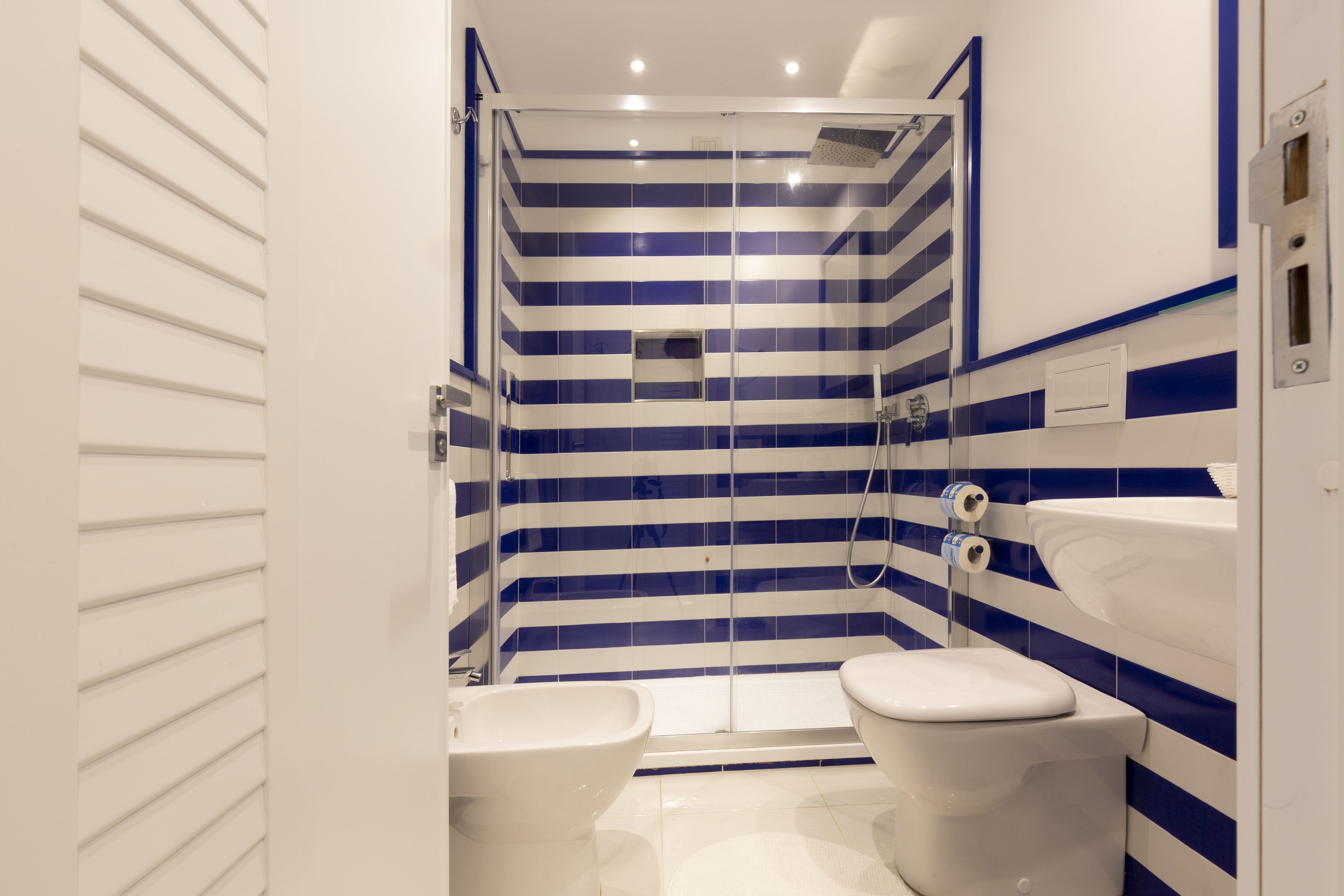 A bathroom with a shower, two toilets, and a sink.