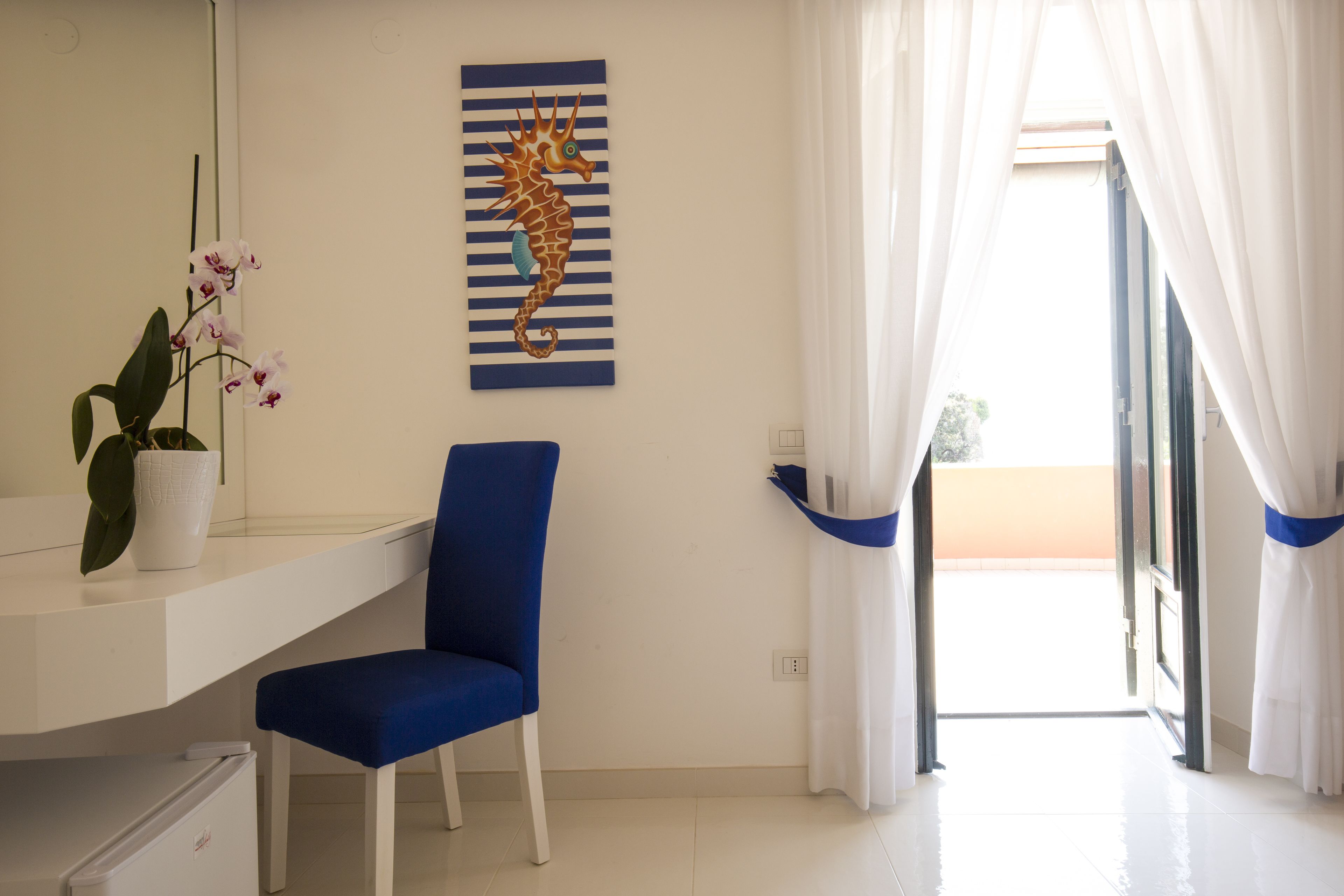 Une pièce comprenant un bureau, une chaise, une plante en pot et une œuvre d’art représentant un hippocampe.
