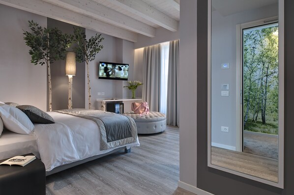 Un dormitorio moderno con cama, mesita de noche y televisor montado en la pared.