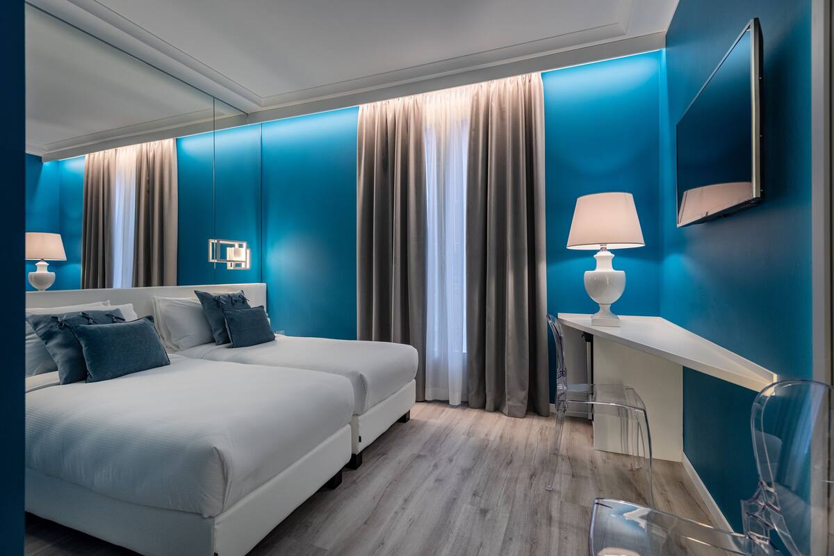 A modern hotel room with a large bed, a desk, and a chair.