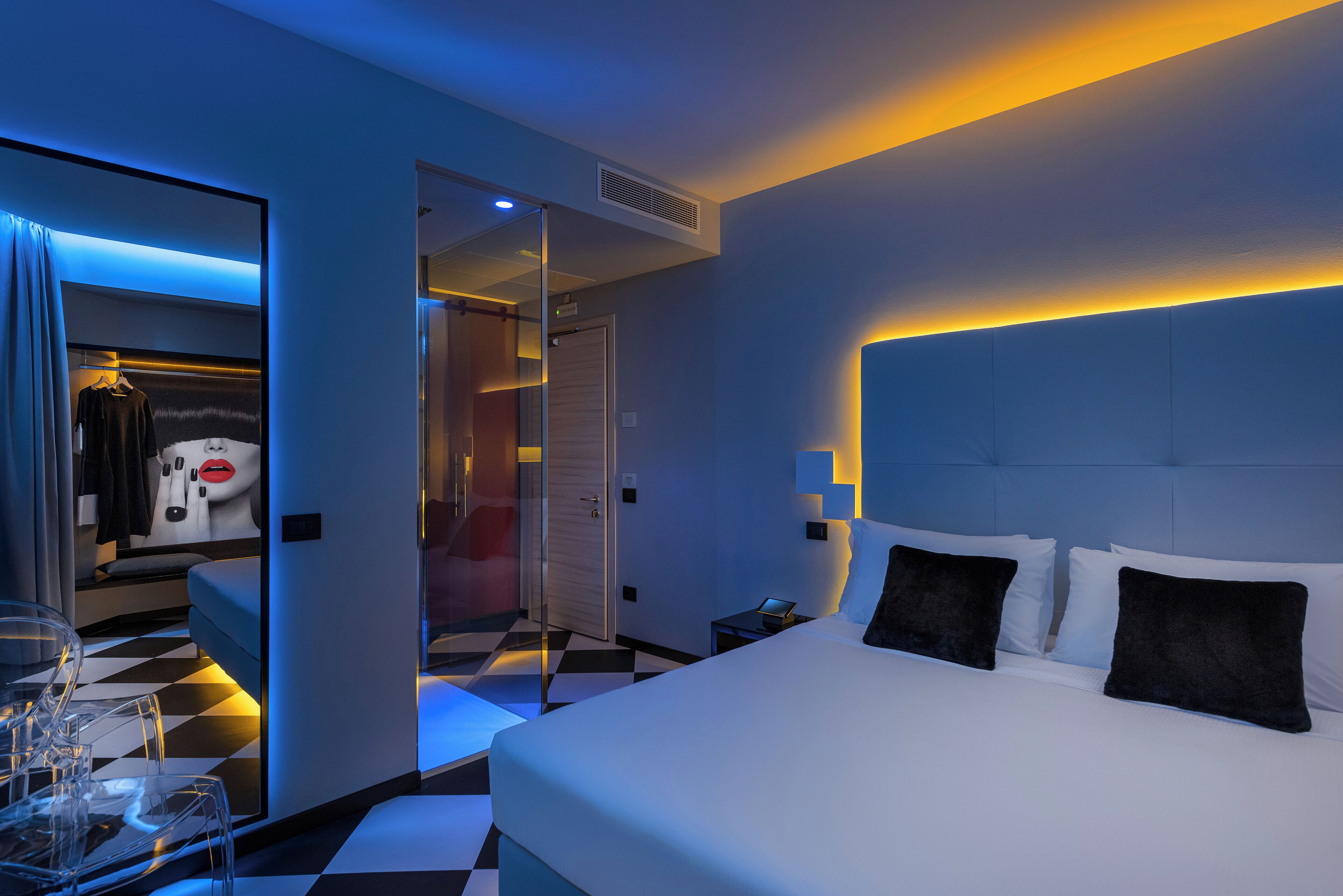 Ein modernes Hotelzimmer mit einem großen Bett, Nachttischen, einem Kleiderschrank und einem karierten Boden.