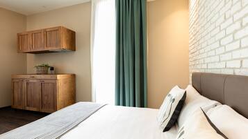 Une chambre à coucher avec un lit, une armoire en bois, une fenêtre avec des rideaux et un mur en briques.