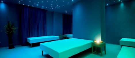Una habitación con una cama, dos mesitas de noche, un banco y una pequeña mesa con una lámpara.
