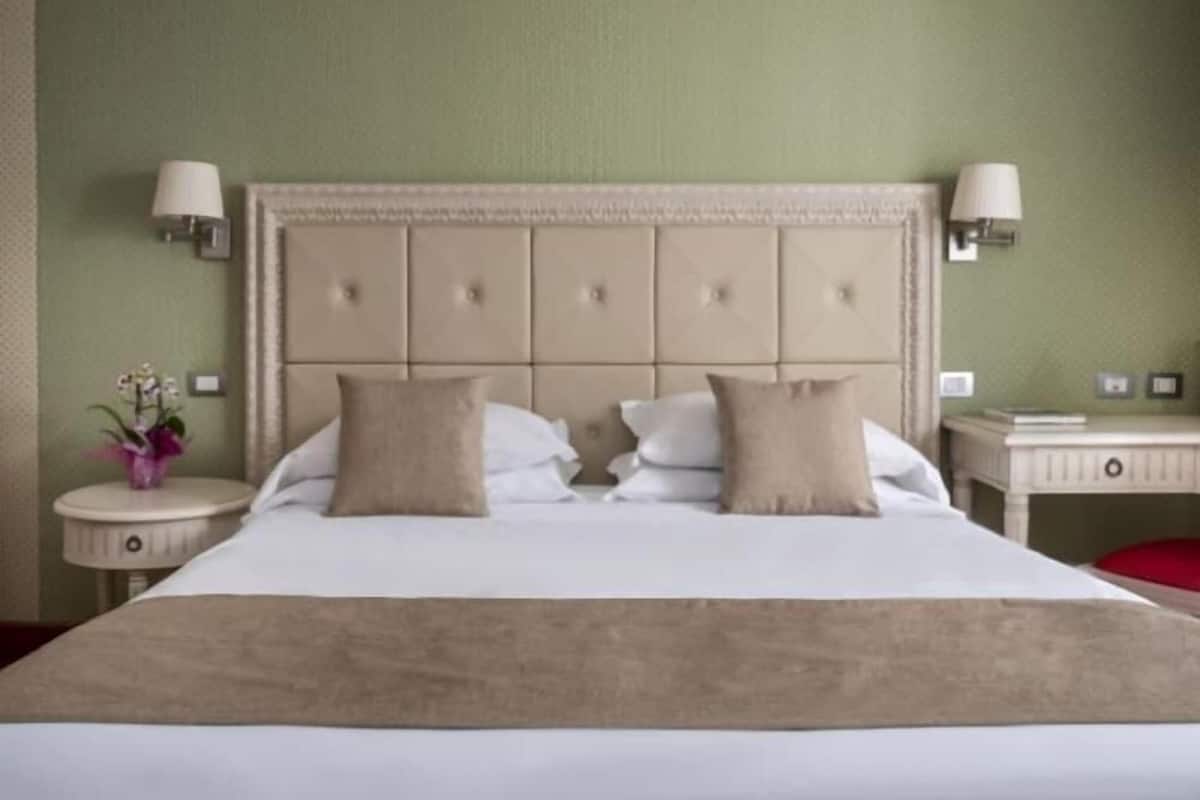 Een hotelkamer met een groot bed, twee nachtkastjes, een wandlamp en een nachtkastje.