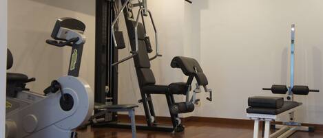 A gym with cardio machines, weightlifting equipment, and a bench.