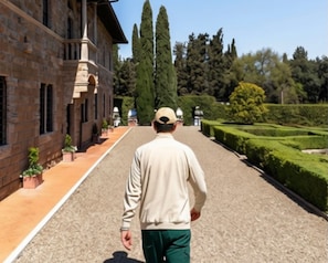 A man walking on a paved pathway towards a building with a brick facade and columns.