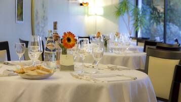 A dining table set with white tablecloths, wine glasses, cutlery, and a bottle of SANTELLE wine.