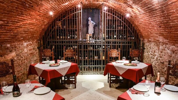 A restaurant with brick walls and arched ceilings, featuring tables set with red tablecloths and wine glasses. - Residence Antico San Zeno (Verona)