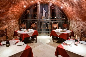 A restaurant with brick walls and arched ceilings, featuring tables set with red tablecloths and wine glasses. - Residence Antico San Zeno (Verona)