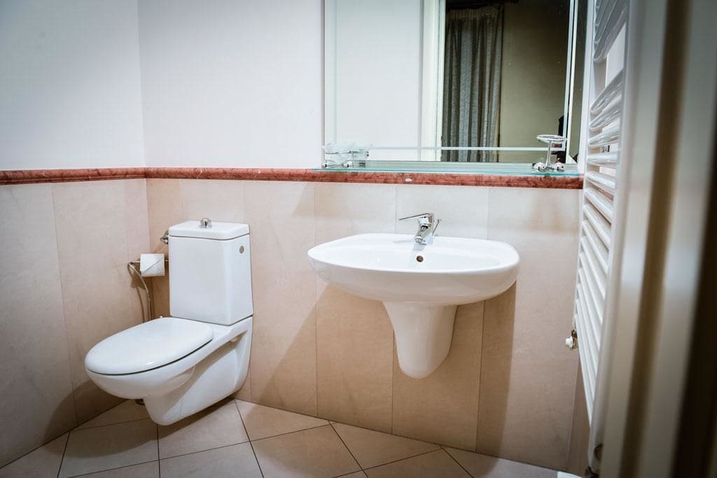 A small bathroom with a toilet, sink, and mirror.