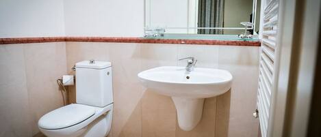 A small bathroom with a toilet, sink, and mirror.
