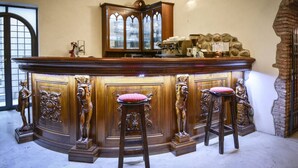 A bar area with a wooden counter, bar stools, and a decorative cabinet. - Residence Antico San Zeno (Verona)
