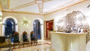 A lobby with a marble reception desk, arched windows, and a decorative wall. - Residence Antico San Zeno (Verona)