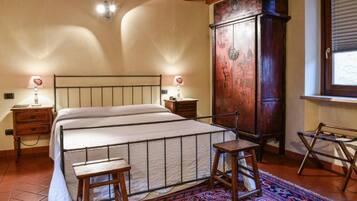 Une chambre avec un grand lit, des tables de chevet en bois, une armoire et une fenêtre avec des stores.