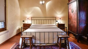 A bedroom with a large bed, two bedside tables, a wooden wardrobe, and a patterned rug. - Residence Antico San Zeno (Verona)