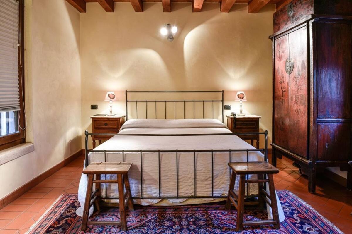 A bedroom with a bed, bedside tables, a wooden cabinet, and a patterned rug.