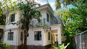 Un edificio de dos plantas con balcón, escalera y entrada cubierta.